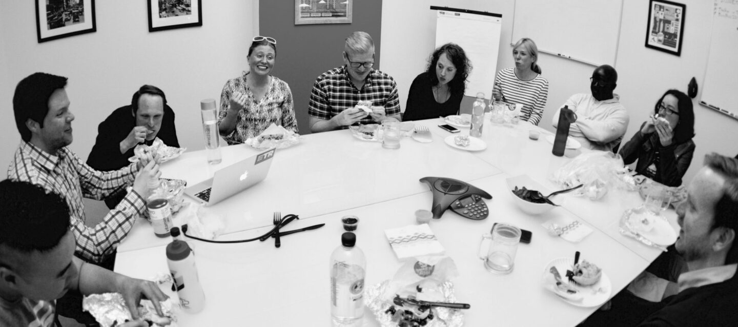 The whole ETR team gather around a conference table eating